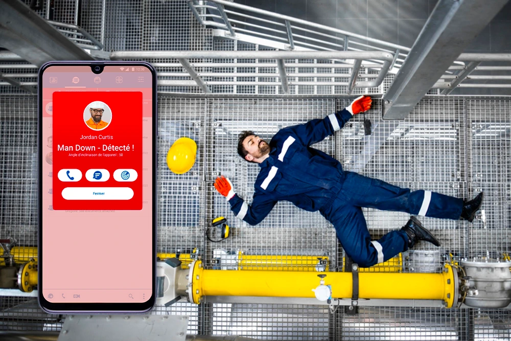 Isolated worker on the ground in a factory, equipped with an alert device to signal an emergency situation.